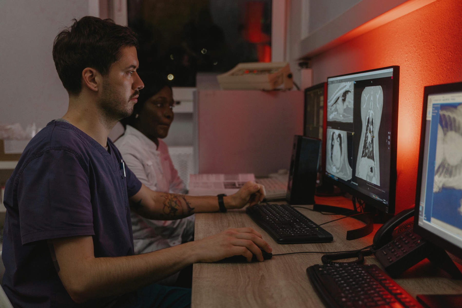 Clinicians reviewing medical imaging scans on workstation screens